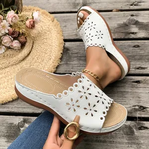 White floral laser-cut platform wedge sandals shown in a summer beach boardwalk setting