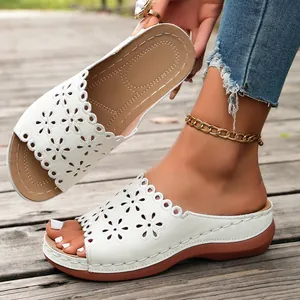 Close-up of white women's wedge sandals featuring intricate hollow-out floral patterns