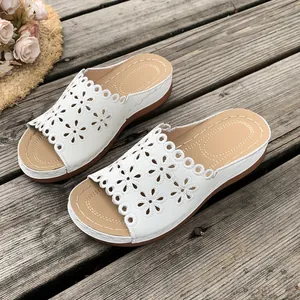 Detailed view of white wedge sandals with intricate laser-cut floral patterns and lace trim