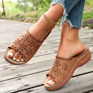 Close-up of brown laser-cut floral sandals with thick wedge soles and white stitching.