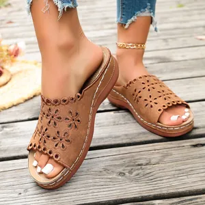 Close-up of brown wedge sandals with cutout flower pattern and white stitching