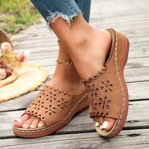 Brown wedge sandals for women with an elegant floral cutout design on wooden deck