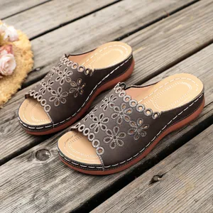 Close-up of brown floral cutout wedge sandals on a rustic wooden background.