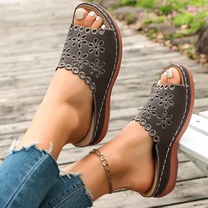 Detail view of women's platform slide sandals with flower cutouts on a wooden deck