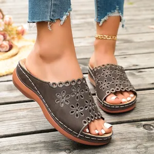 Stylish women's platform slide sandals with intricate laser-cut floral details on wood.