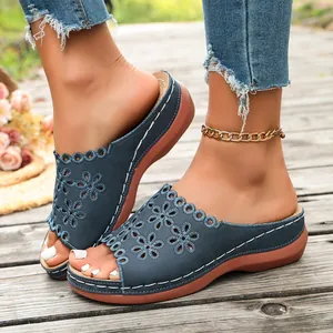 Close-up detail of women's blue peep-toe wedge sandals with laser-cut floral pattern