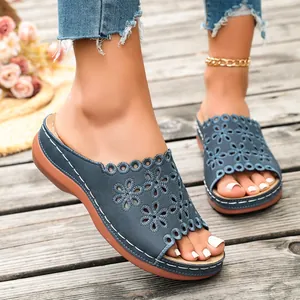 Detail view of blue platform wedge sandals with hollow-out floral pattern and white stitching