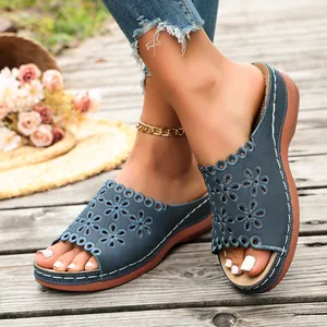 Detail view of blue wedge sandals with laser-cut floral patterns and a thick white stitched sole
