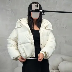 Close-up view of a stylish short white hooded puffer jacket worn by a model in a studio