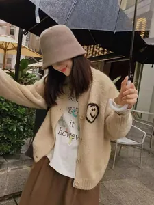 Lifestyle detail of a cream knitted cardigan featuring hand-drawn smiley face embroidery