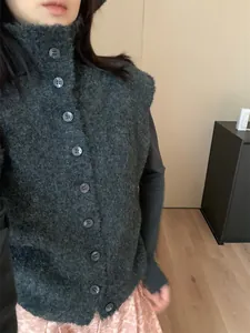 Gros plan d'un gilet en maille bouclée gris foncé avec col montant et boutons devant