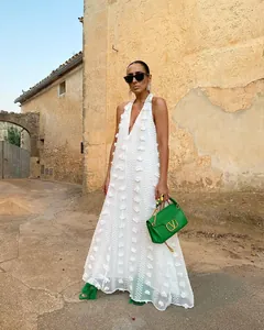Modèle portant une robe longue blanche dos nu à fleurs 3D dans un décor rustique