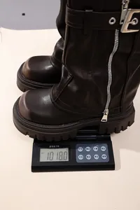 Close-up detail of dark brown leather square-toe motorcycle boots on weight scale