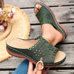 Detail view of olive green women's wedge sandals with decorative floral cut-out pattern