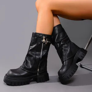 Close-up detail of black leather platform biker boots with metal zippers and buckles