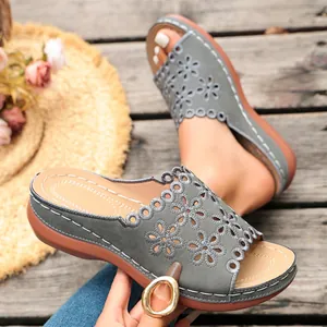 Close-up detail of women's grey wedge sandals featuring elegant laser-cut floral patterns.