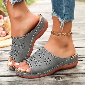 Close-up detail of gray women's platform slide sandals with floral laser-cut patterns