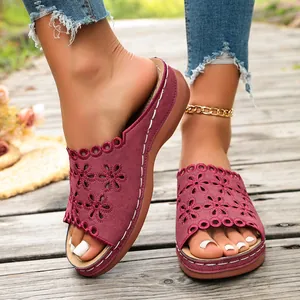 Detailed view of burgundy wedge sandals with laser-cut floral patterns and contrast stitching