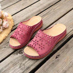 Close-up of wine red wedge sandals with laser-cut floral patterns and contrast stitching.