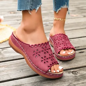 Detailed view of burgundy wedge sandals featuring intricate laser-cut floral patterns