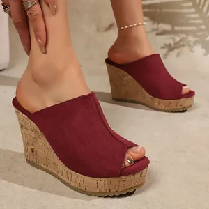 Detail view of wine red suede wedge sandals with cork platform and peep-toe design.