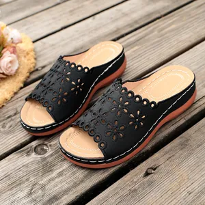 Detailed view of women's wedge sandals with black laser-cut floral upper and thick sole