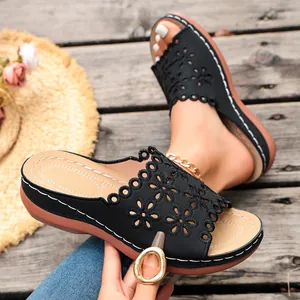 Close-up of black platform sandals with laser-cut floral patterns and contrast stitching.