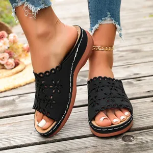 Close-up of women's black wedge sandals featuring intricate laser-cut floral details