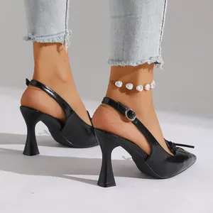 Detail of black patent leather pointed-toe slingback heels with elegant bow decoration.