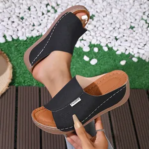 Close-up of black platform wedge sandal with floral laser-cut details and white stitching.