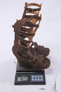 Detailansicht des Gewichts von 615 g für braune kniehohe Keilsandalen auf einer Waage