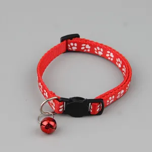Macro-detail van een rode kattenhalsband met witte pootafdrukken en een klein belletje