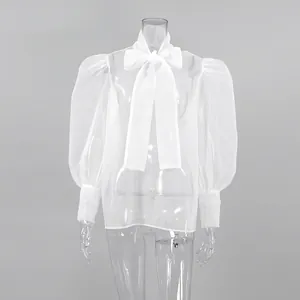 Detalle de blusa de malla blanca transparente con mangas abullonadas y lazo