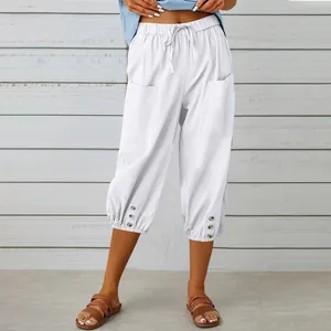 Close-up detail of white linen cropped pants with drawstring waist and decorative buttons.