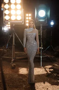 Robe de soirée élégante à paillettes argentées avec épaule dénudée en mesh et coupe ajustée.