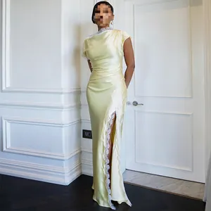 Elegantes gelbes Satin-Maxikleid mit zartem weißem Spitzenbesatz und hohem Beinschlitz.