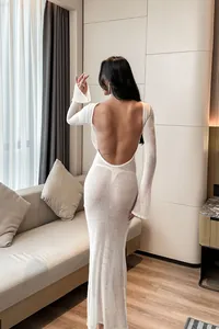 Back view of a white long-sleeved backless mesh beach cover-up dress in a cozy indoor setting.
