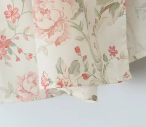 Macro detail of the delicate peach floral print and hem stitching on a cream summer dress