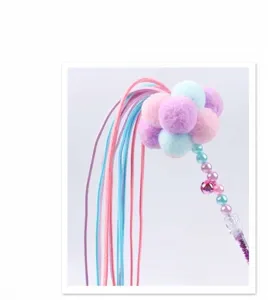 Close-up of cat teaser wand with pastel plush balls, ribbons, and small bell details.