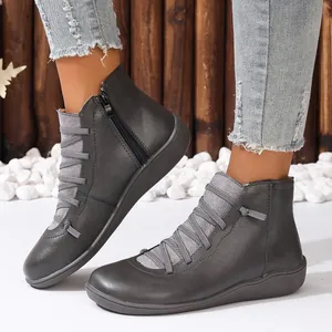 Détail de bottines grises pour femmes avec brides décoratives et fermeture éclair