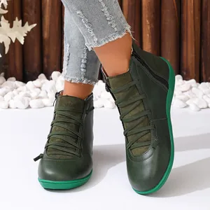 Gros plan de bottines à lacets vertes avec fermetures éclair portées avec un jean bleu