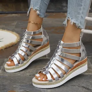 Detail of silver metallic gladiator platform sandals with rear zipper and espadrille sole.