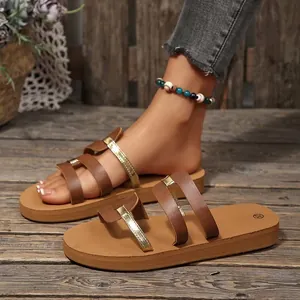 Detail view of brown and gold flat casual slides for women on wooden floor