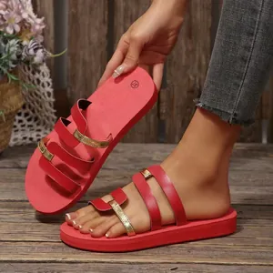 Close-up of red and gold multi-strap flat casual sandals for women on a wooden floor