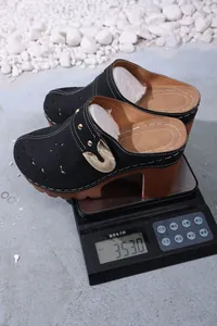 Sabots noirs à talons épais avec boucle dorée pesant 353 grammes sur une balance