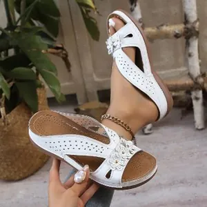 Vue détaillée des sandales compensées blanches vintage avec fleurs et détails découpés.
