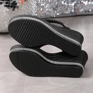 Detalle de chanclas de cuña negras con pedrería y suela de plataforma antideslizante.