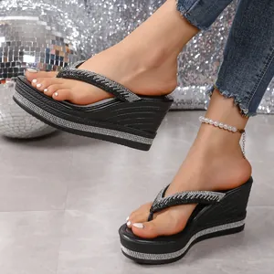 Detalle de chanclas negras con plataforma y tiras decoradas con pedrería brillante