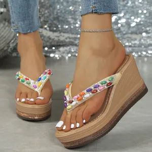 Detalle de sandalias con cuña beige para mujer decoradas con cuentas de colores y perlas.