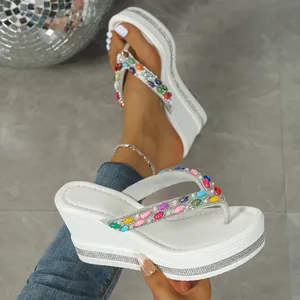 Detalle de chanclas blancas con cuña decoradas con diamantes de imitación multicolor
